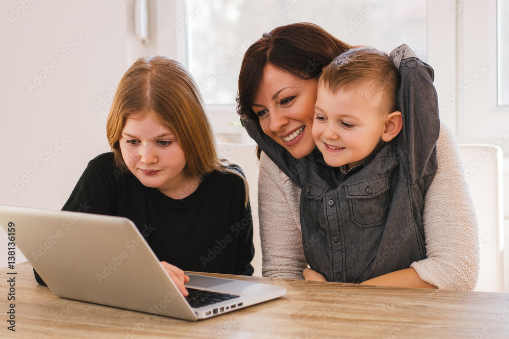 Mom and kids earching for family pictures on computer at home.