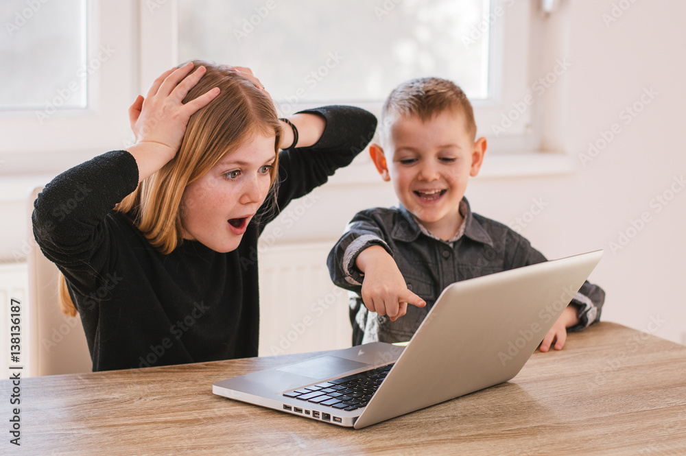 Suprised kids looking at laptop screen at home