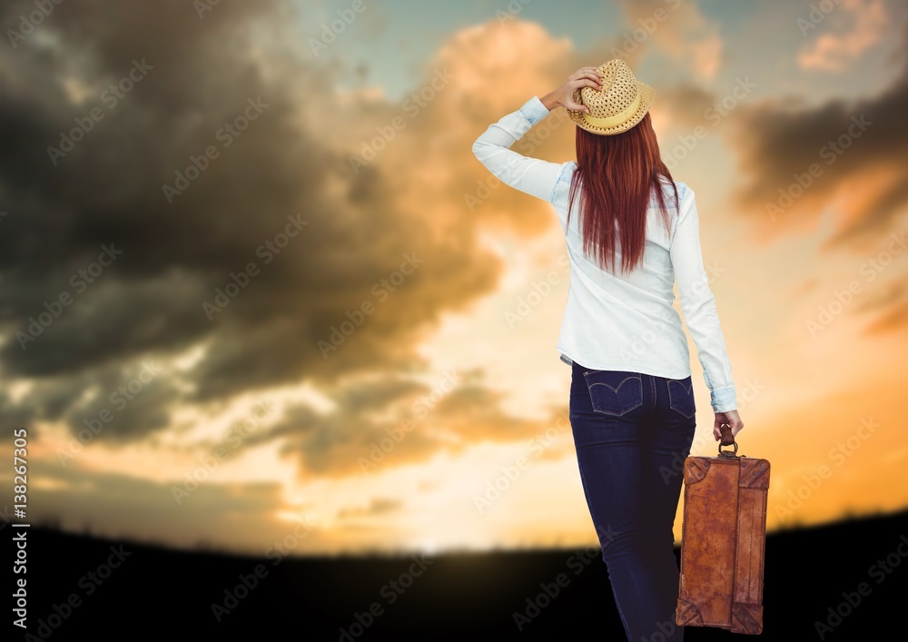 Woman holding Luggage against sky background 