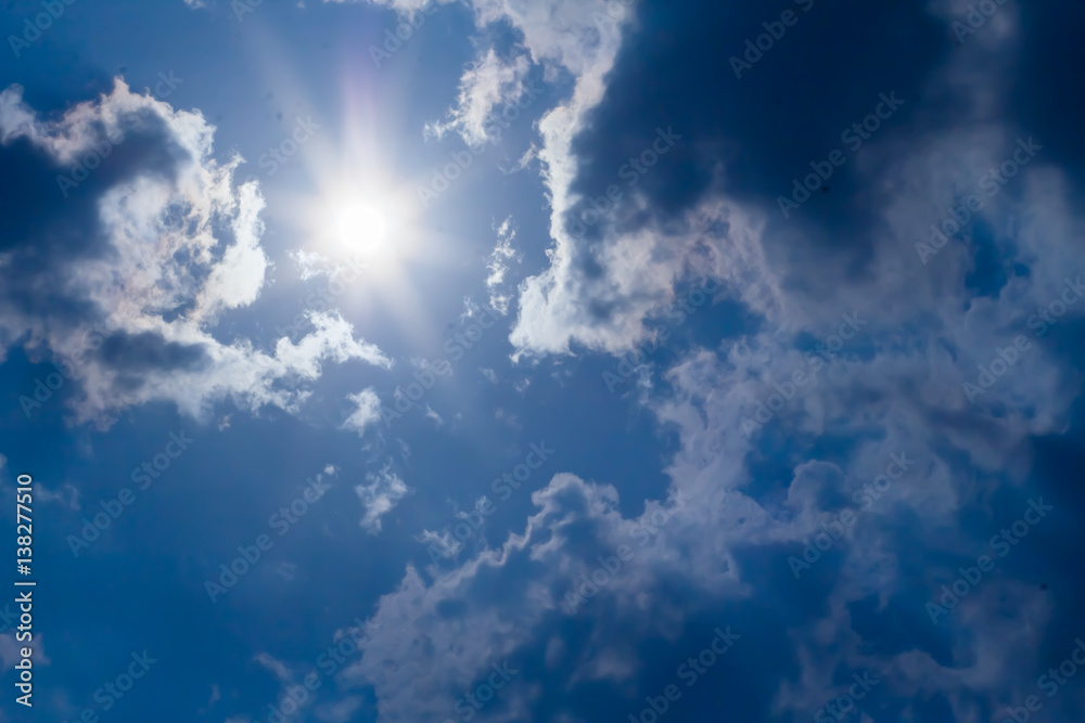 sun with sunbeams in a beautiful cloudy sky. blue sky is covered by white clouds