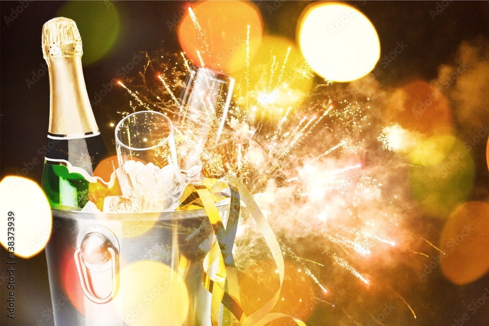 Bottle champagne with glasses in bucket on firework background.