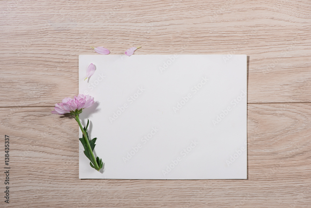 Pink flowers and empty paper for your text on wooden background