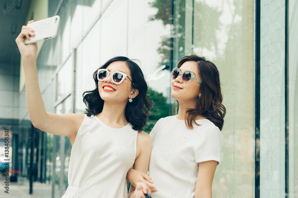 Beautiful asian girls with shopping bags taking selfie photo at the mall