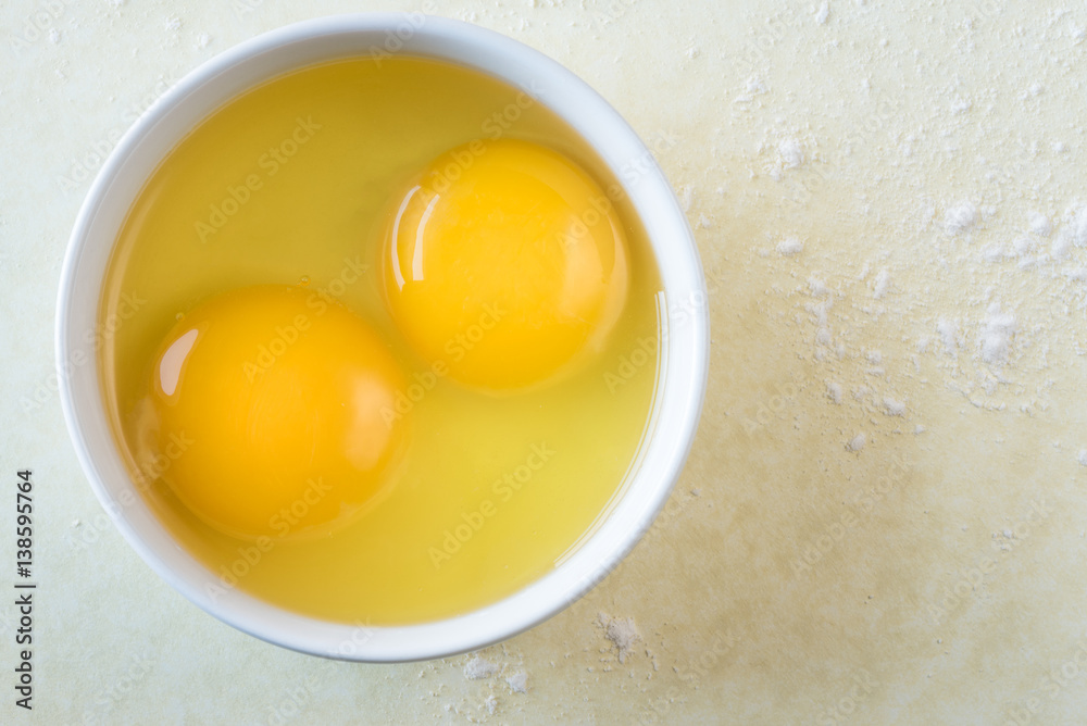 Egg yolks in a bowl on yellow background