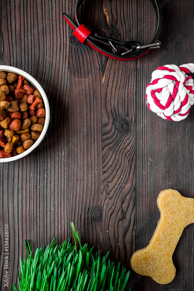 dry dog food in bowl on wooden background top view