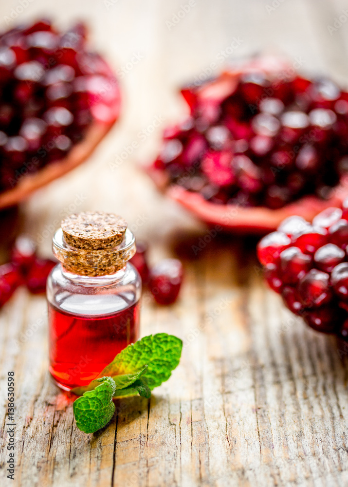 sliced pomegranate and extract in glass on wooden background