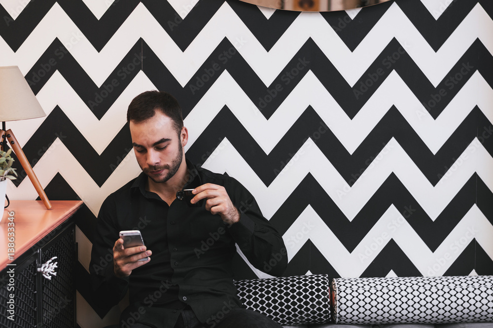 Guy drinking first morning coffee while checking emails on mobile