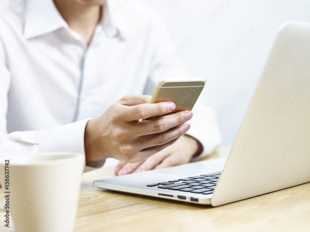 young man using cellphone and laptop