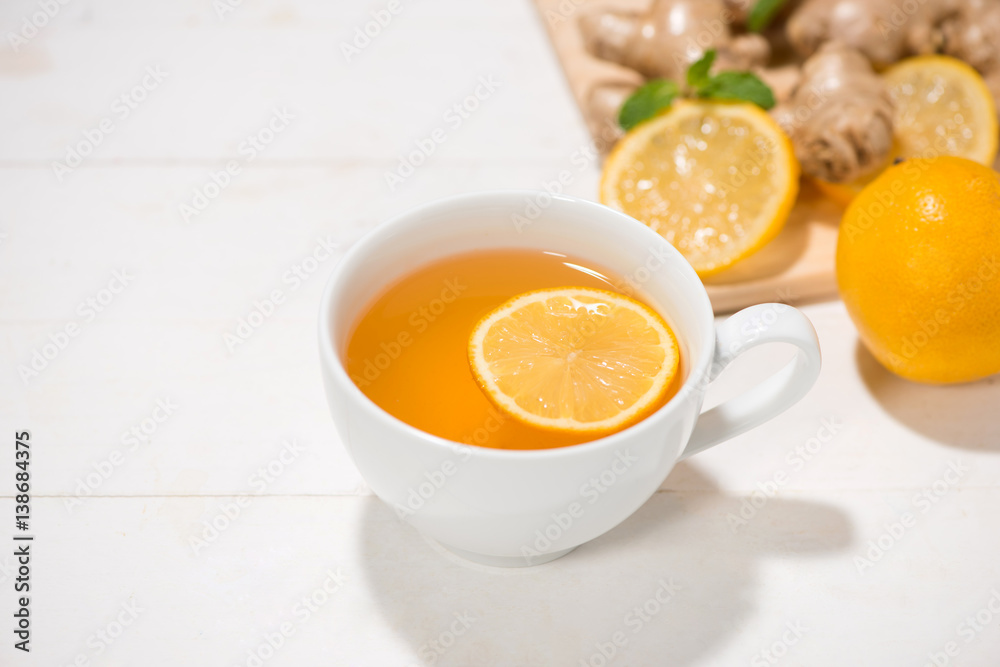 Cup of Ginger Tea with Lemon and Honey on a White Wooden Background.