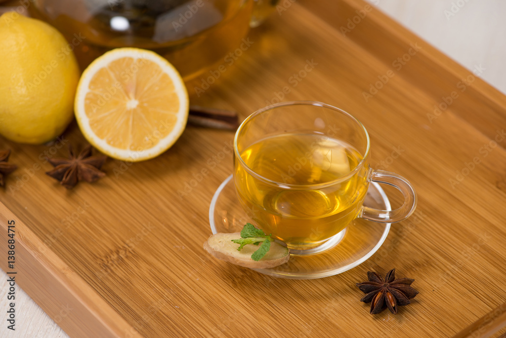 Cup of ginger tea with lemon and honey on white wooden background.