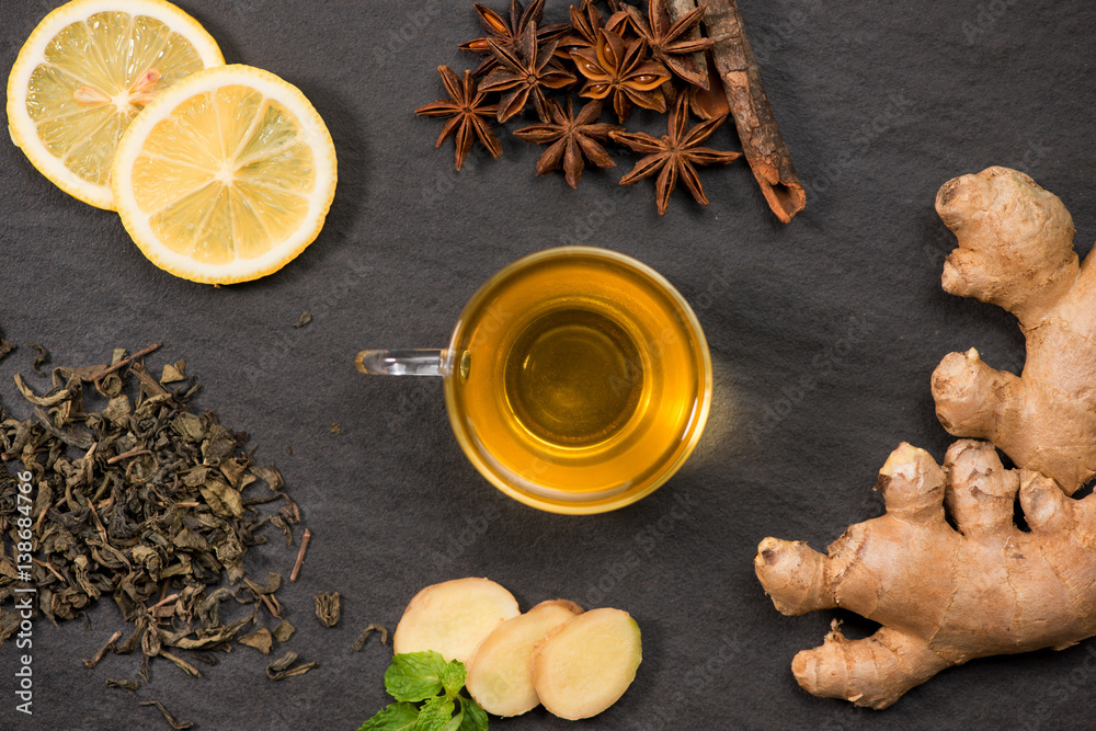 Cup of ginger tea with lemon and honey on dark stone background