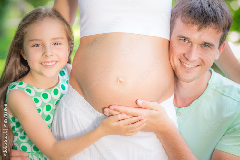 Happy family holding belly of pregnant woman