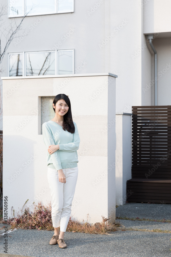 attractive asian woman standing front of modern house