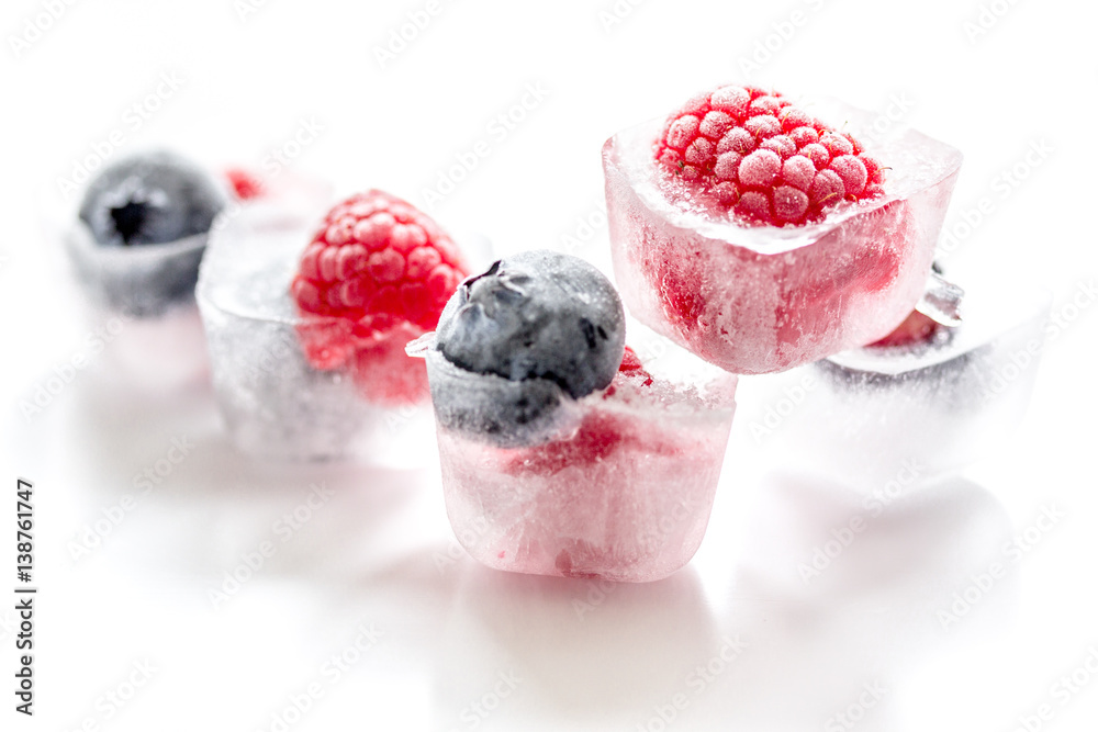 Ice cubes with frozen berries on white background