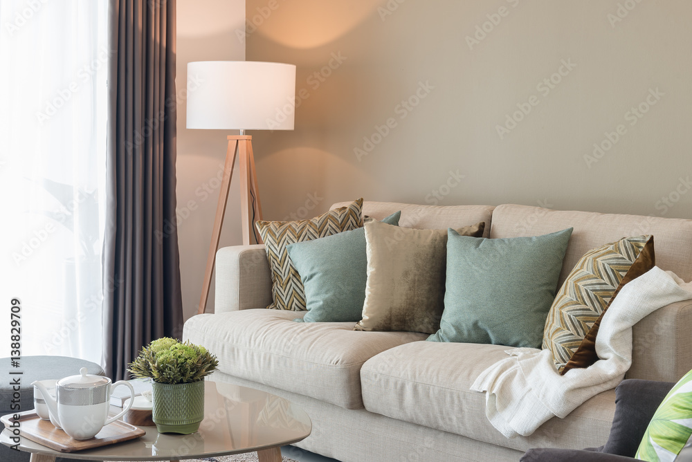 modern living room with green pillows on cozy sofa and wooden lamp