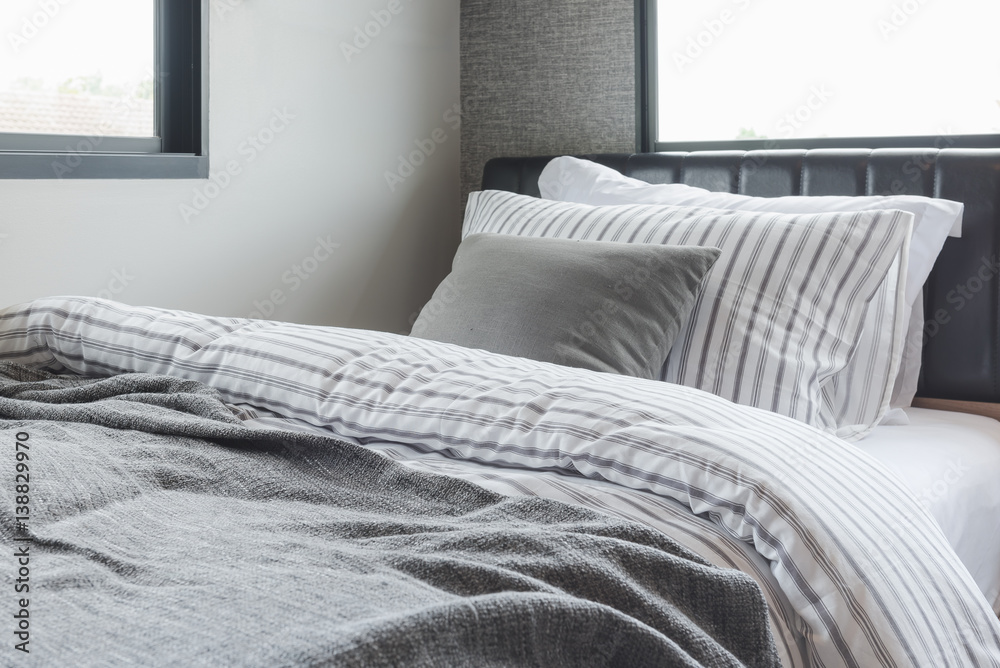 set of pillows with blanket on modern wooden bed