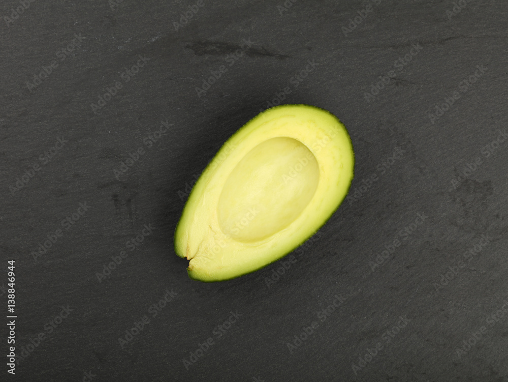 Fresh ripe green avocado on black slate board