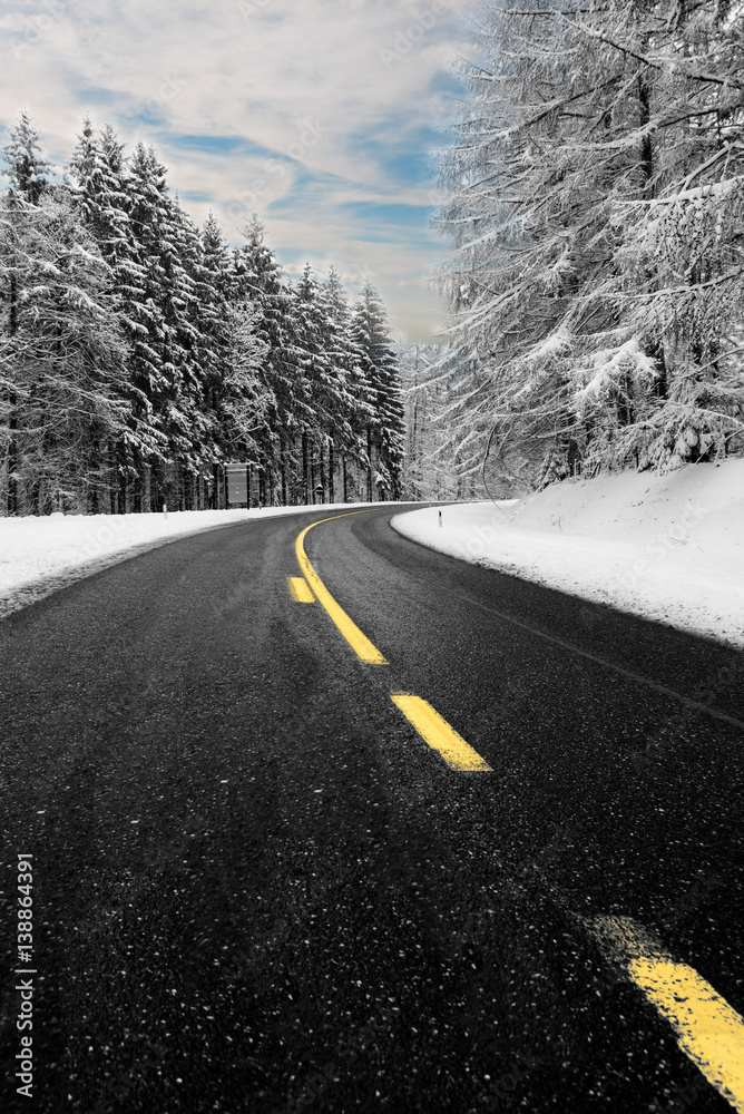 Route enneigée à la Baraque de Fraiture en Belgique. Ligne jaune et ciel bleu pour une photo en noir