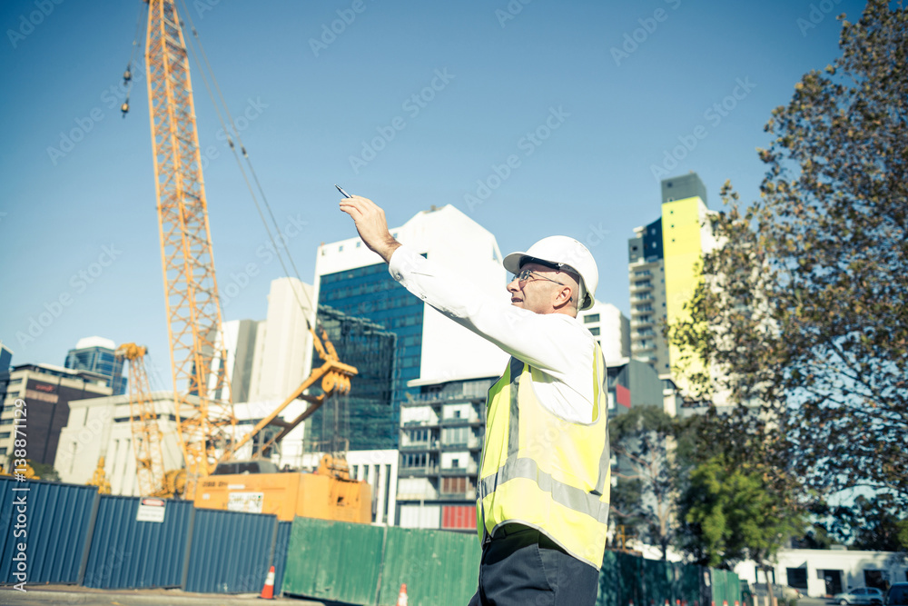 Senior foreman in glasses doing his job at building area on sunn