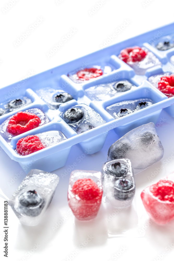 blueberry and raspberry in ice tray on stone background