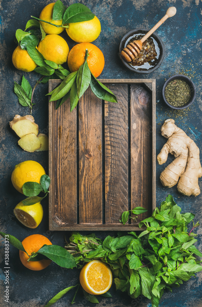 Ingredients for making natural hot drink with wooden tray in center. Oranges, mint, lemons, ginger, 