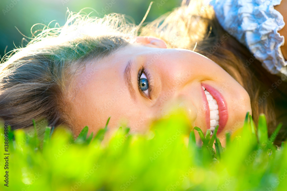 Beautiful teenage girl lying on green grass outdoor