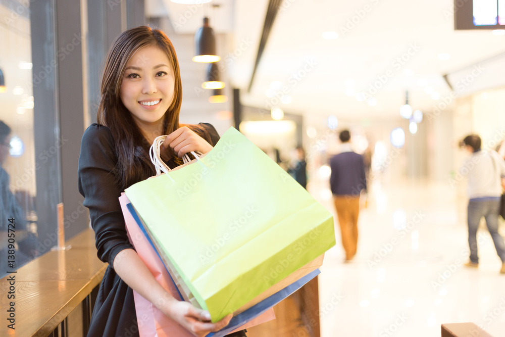 年轻的亚洲女人在现代购物中心购物