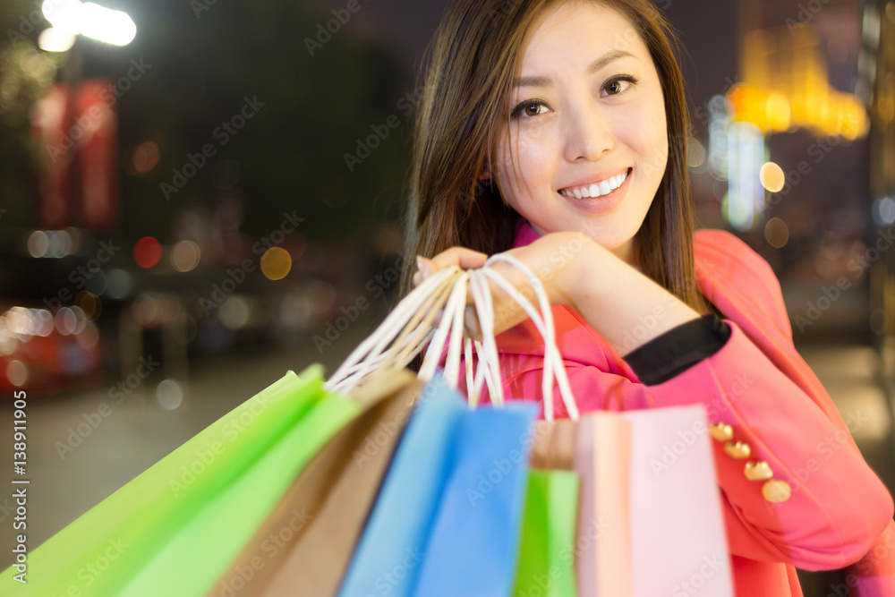 young asian woman with shopping bags on city street