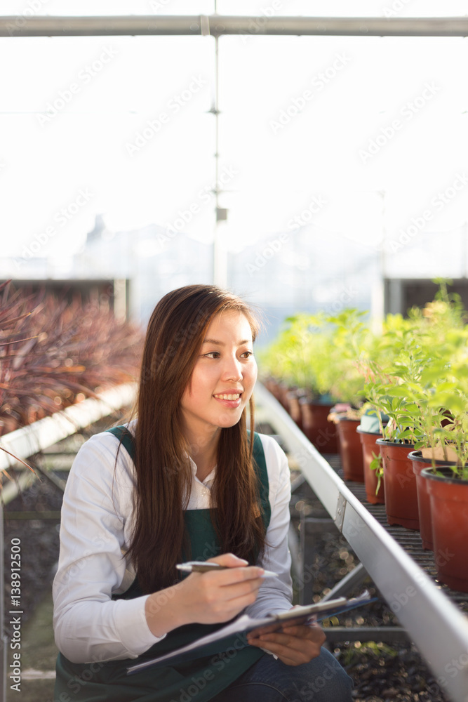 young asian woman works in green house