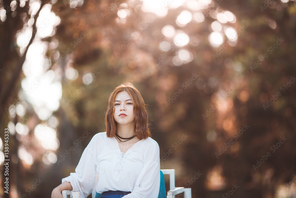 Portrait of young hipster Asian girl posing in the autume park forest bokeh background