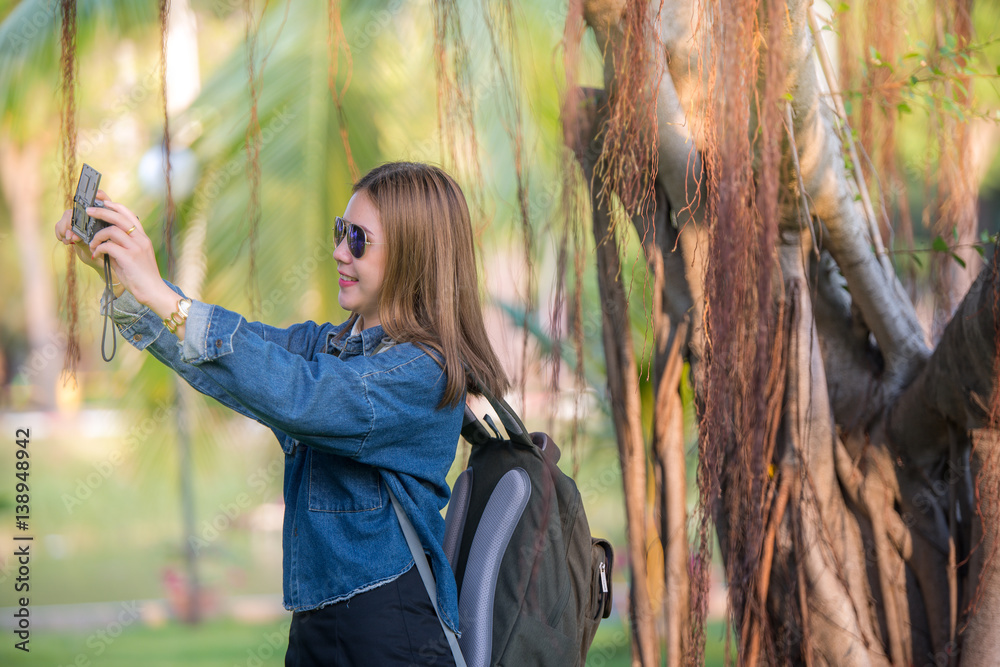 Beautiful Asian traveler taking selfie with forest view background.