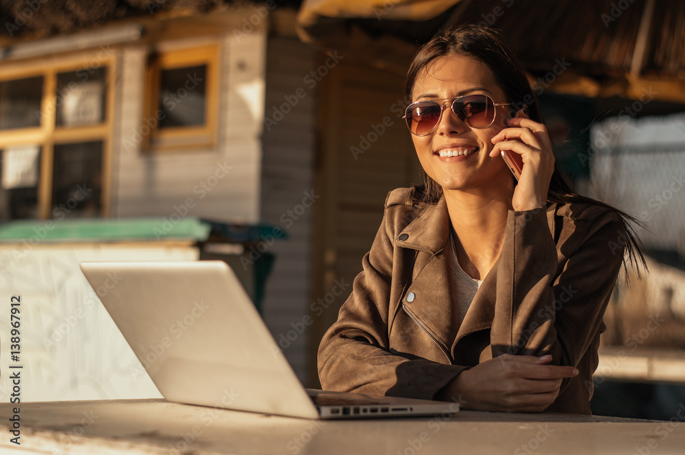 Girl talking on the phone while working on computer outdoor