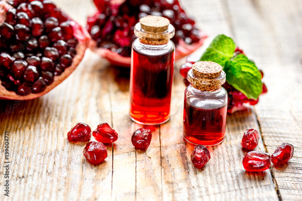 sliced pomegranate and extract in glass on wooden background