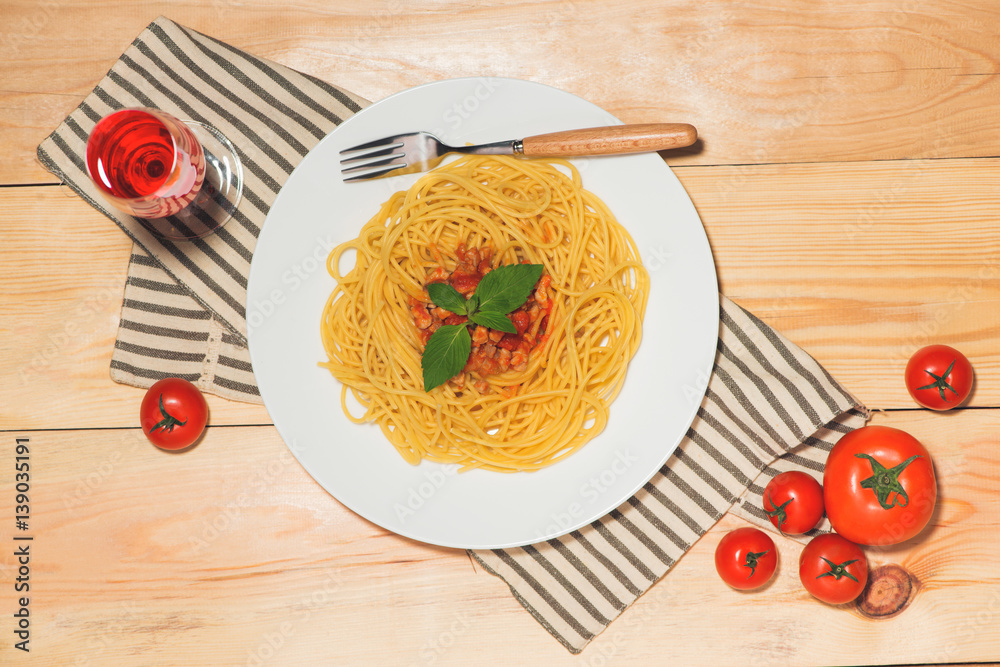 Top view of spaghetti with tomato sauce and meat on wooden table.