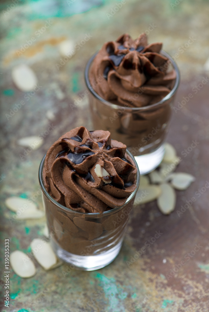 Chocolate mousse with chocolate sauce and almond slices in a glasses on a vintage background.