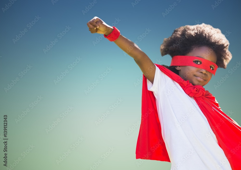 Boy pretending to be a superhero against blue background