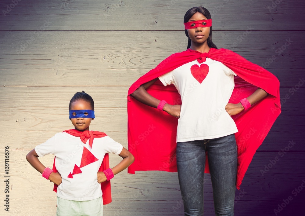 Mother and son in superhero costumes standing with hands on hips