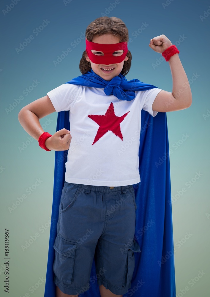 Boy pretending to be a superhero against blue background