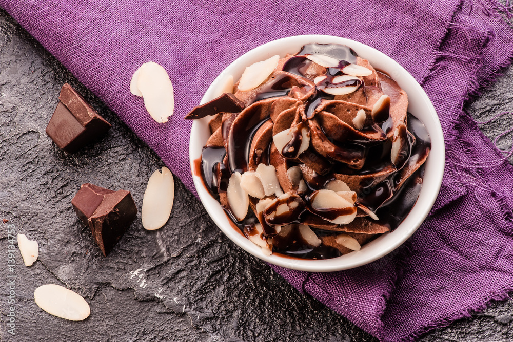 Chocolate mousse with chocolate sauce and chocolate pieces, almond slices in a glasses on a vintage 