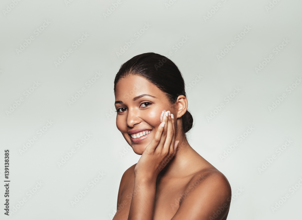 Smiling woman applying moisturizer on her face