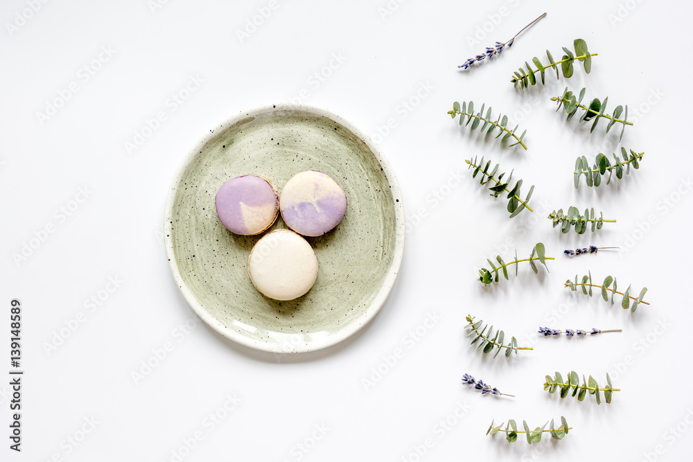 Trendy design with macaroons on plate, eucalyptus and lavander top view