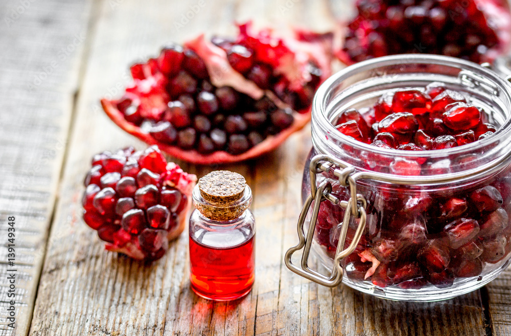 sliced pomegranate and extract in glass on wooden background