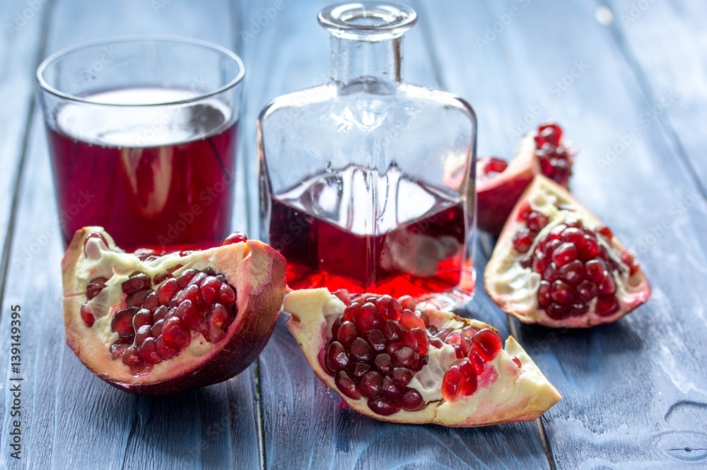 red fruit juice with fresh pomegranate on wooden background