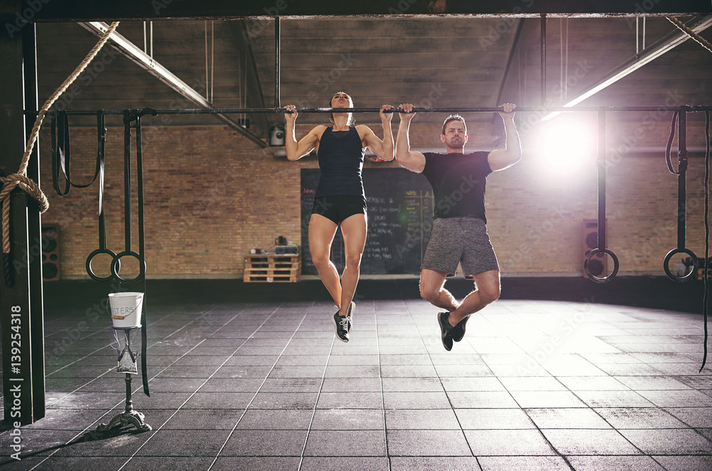 Man and woman doing chin-ups in gym