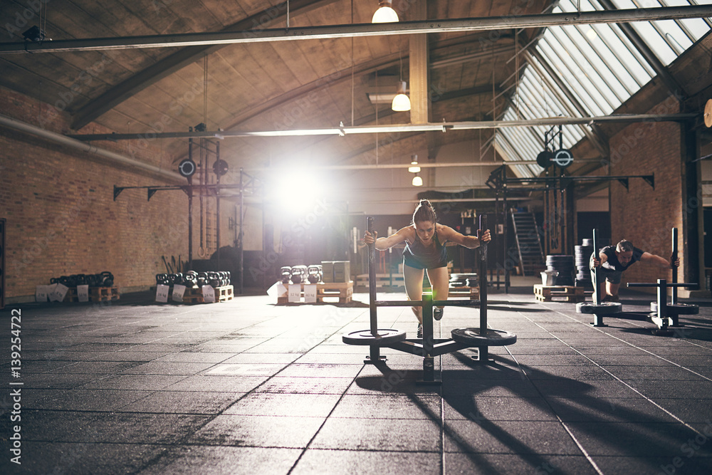 Sportive strong woman pushing bogie with weight