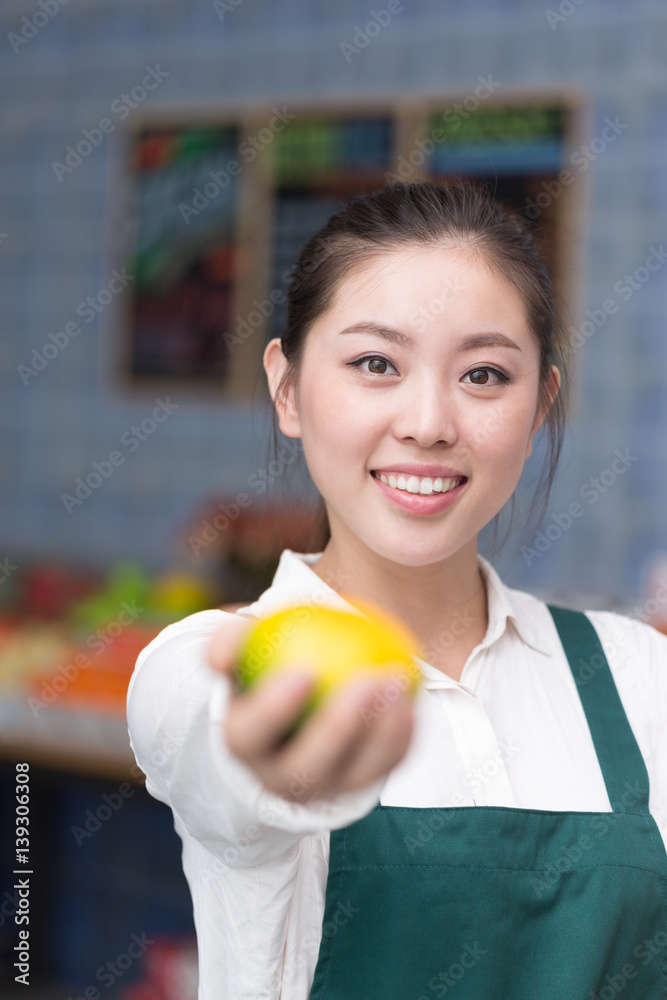 young pretty woman works in fruit store