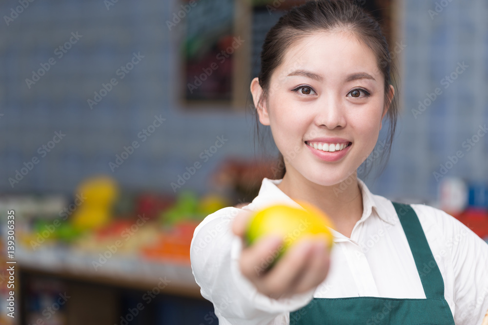 young pretty woman works in fruit store