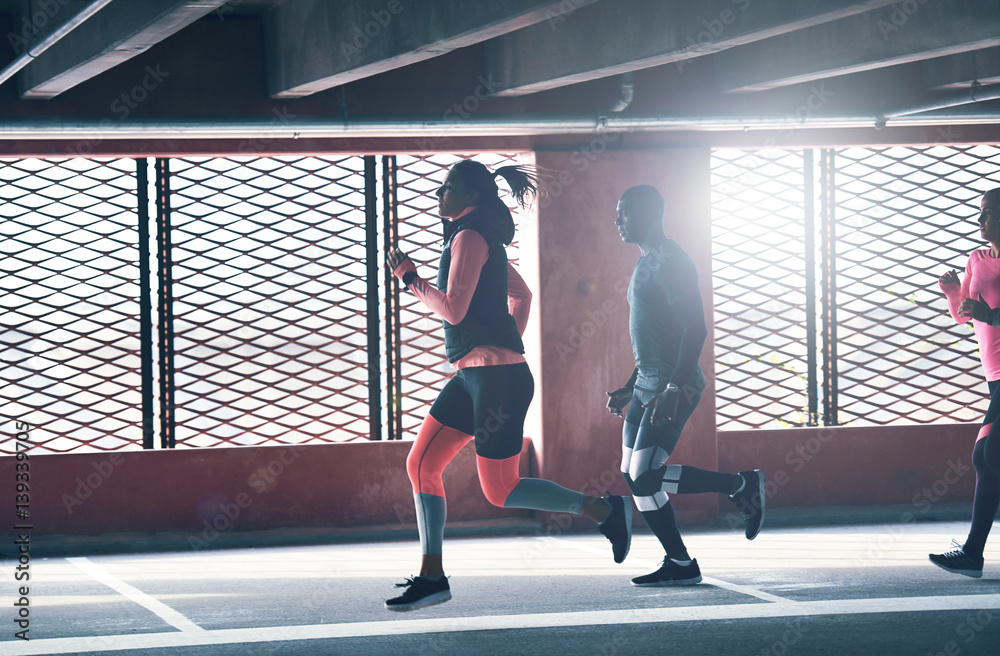 Young friends running through an urban car park