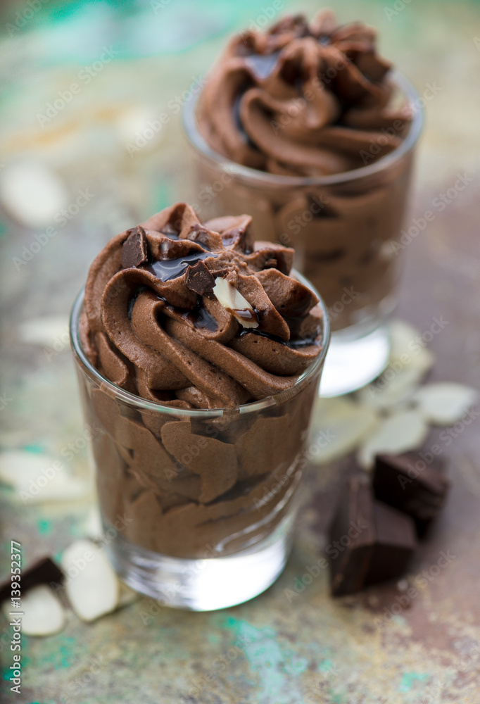 Chocolate mousse with chocolate sauce and chocolate pieces, almond slices in a glasses on a vintage 