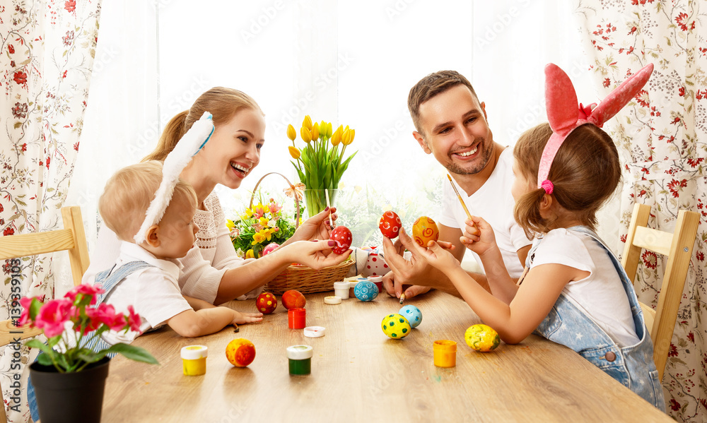 Happy easter! family mother, father and children paint  eggs for holiday.